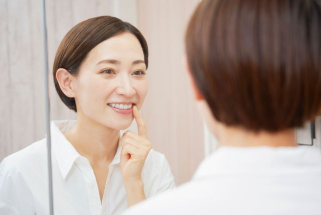 鏡で歯を見ている女性