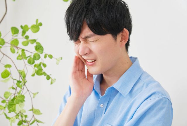 歯に痛みを感じている男性