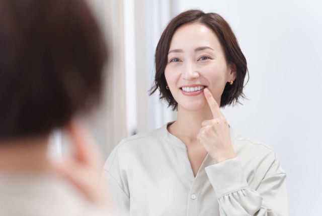 鏡で白い歯を見て微笑む女性