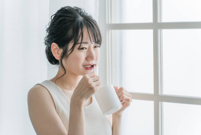 歯磨き中に痛みを感じている女性